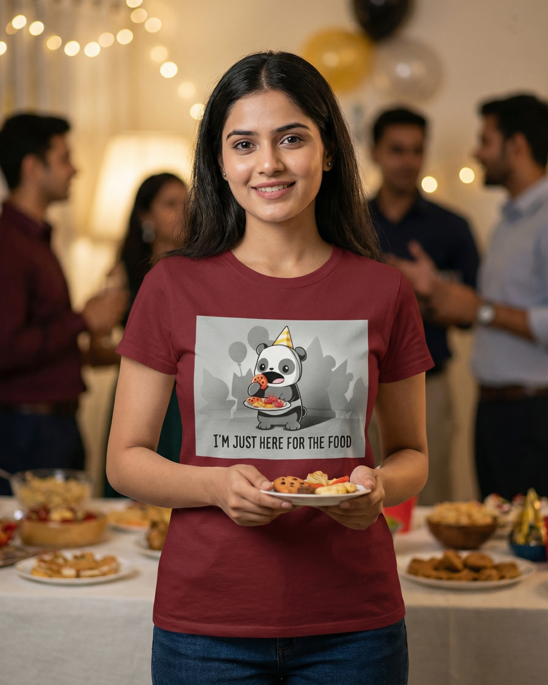 Woman wearing a t-shirt with a panda graphic and text, holding food at a party.